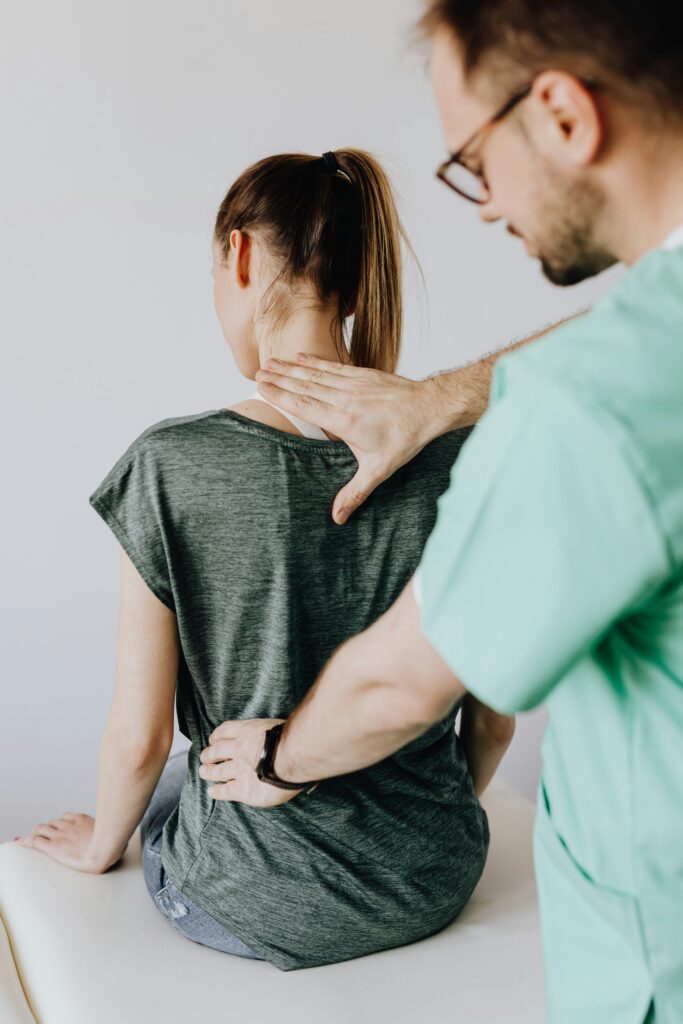 A doctor performs a spine examination on a seated patient at a medical clinic.